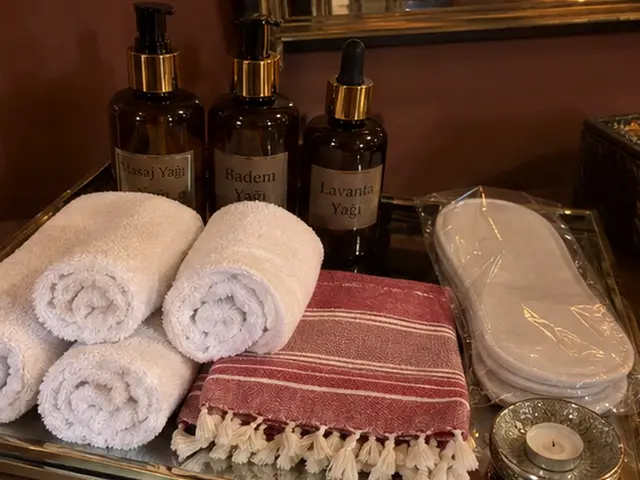 Masaj yağları, rulo havlular, kırmızı çizgili peştemal ve terlik — Karaköy, Masaj Salonun